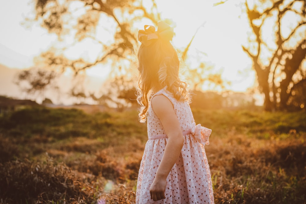 a little girl in a dress walking through a field