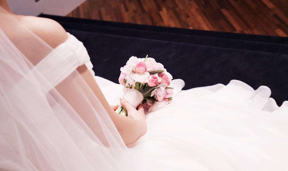 a woman in a wedding dress holding a bouquet of flowers