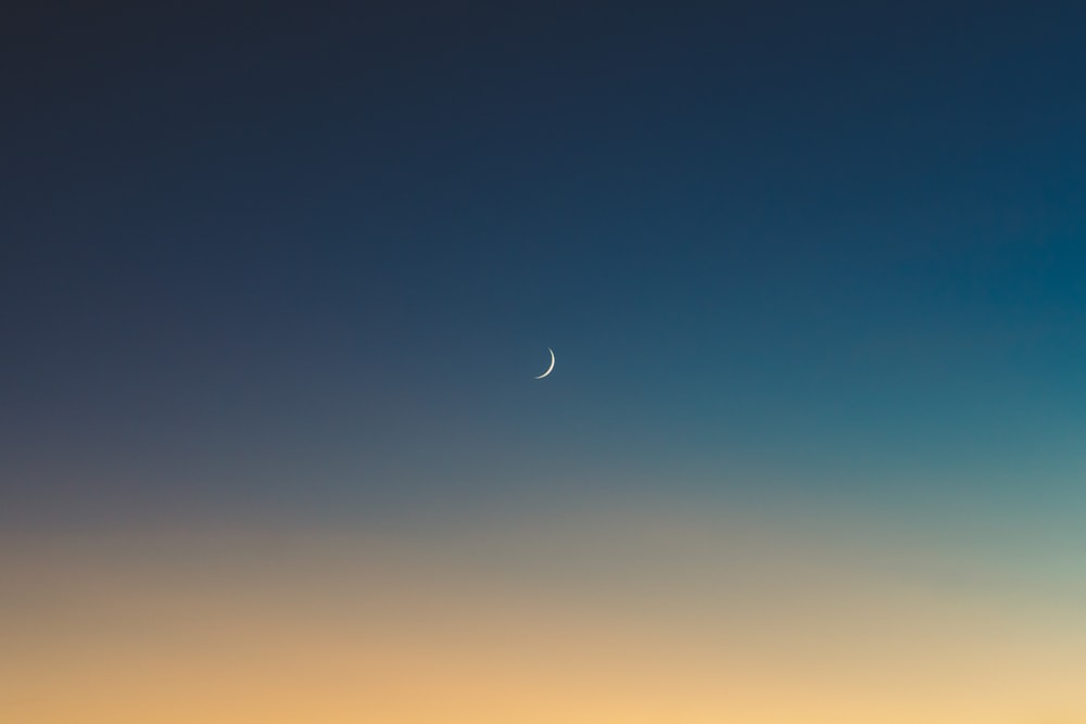 the moon is visible in the sky over the ocean