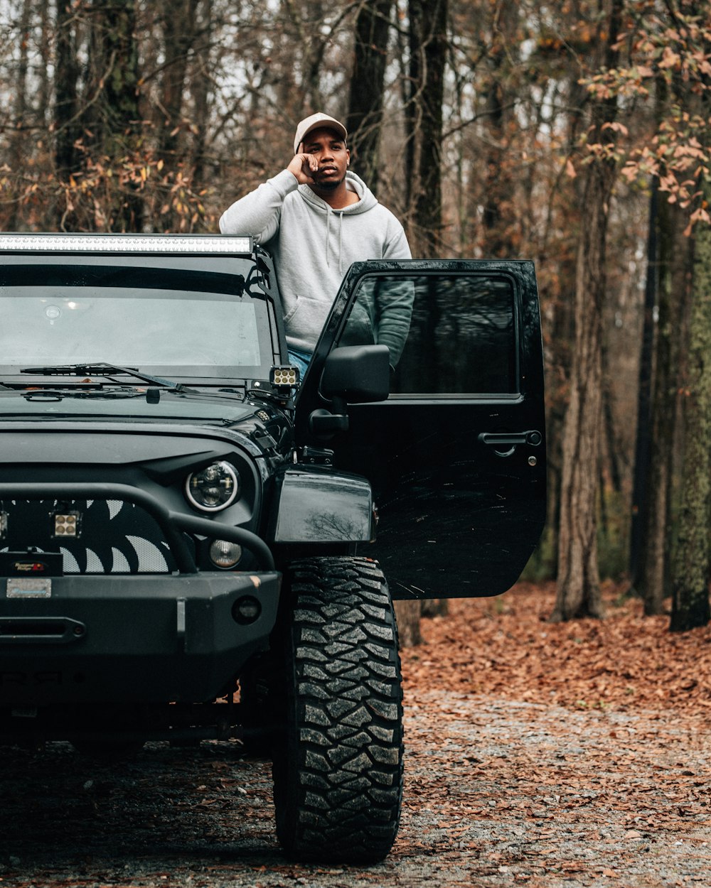 a man standing next to a jeep in the woods
