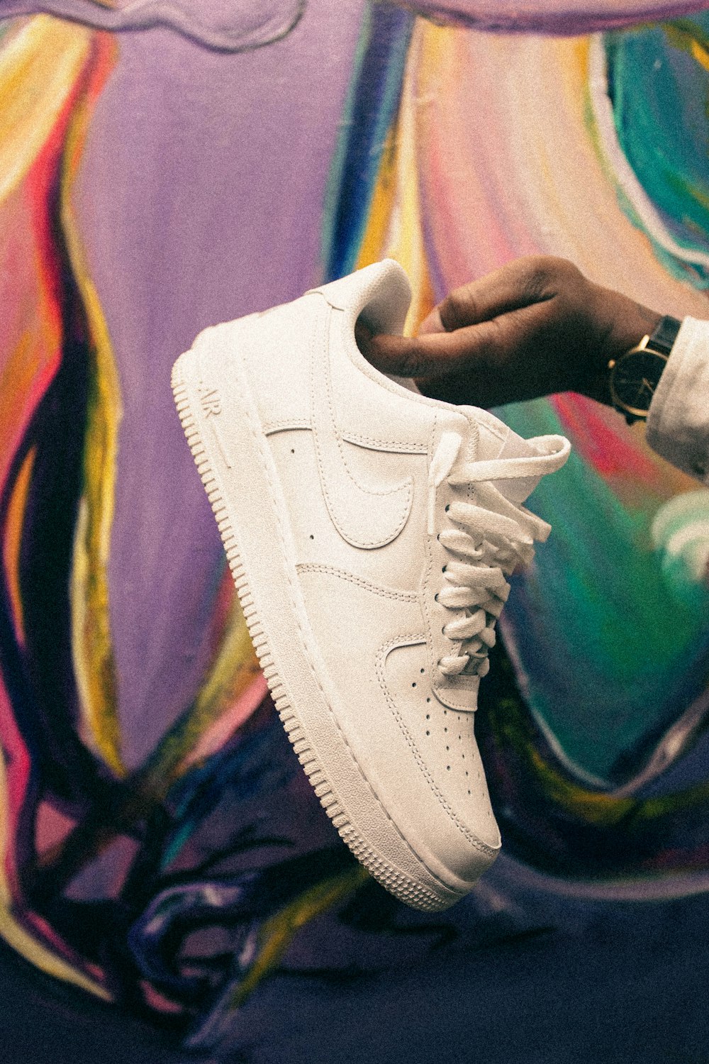 a person holding a pair of white sneakers