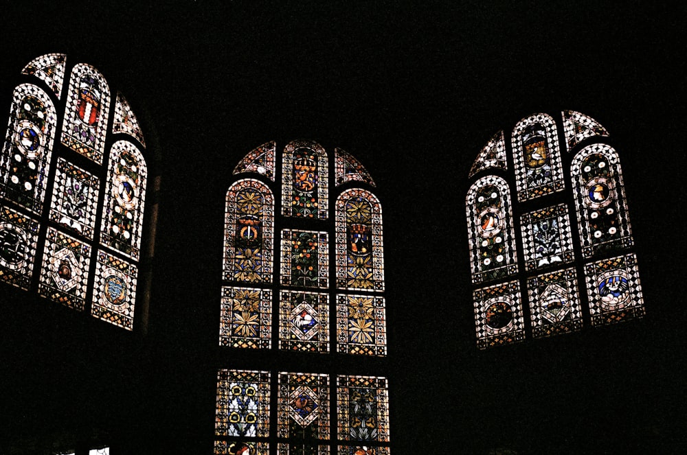 three large stained glass windows in a dark room