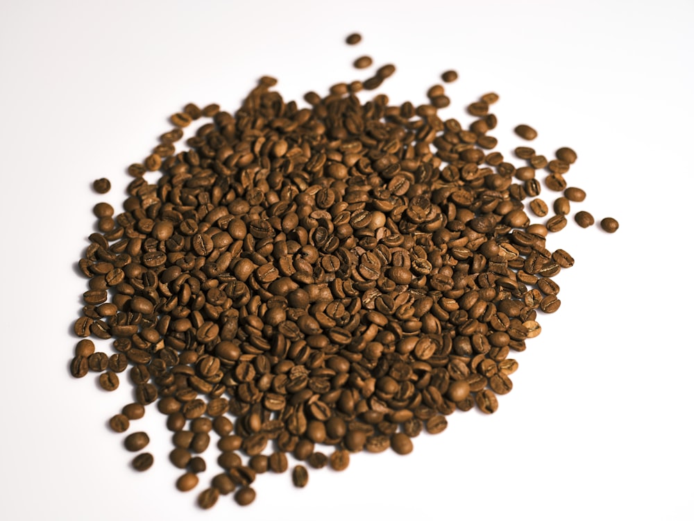Una pila de granos de café sobre una superficie blanca