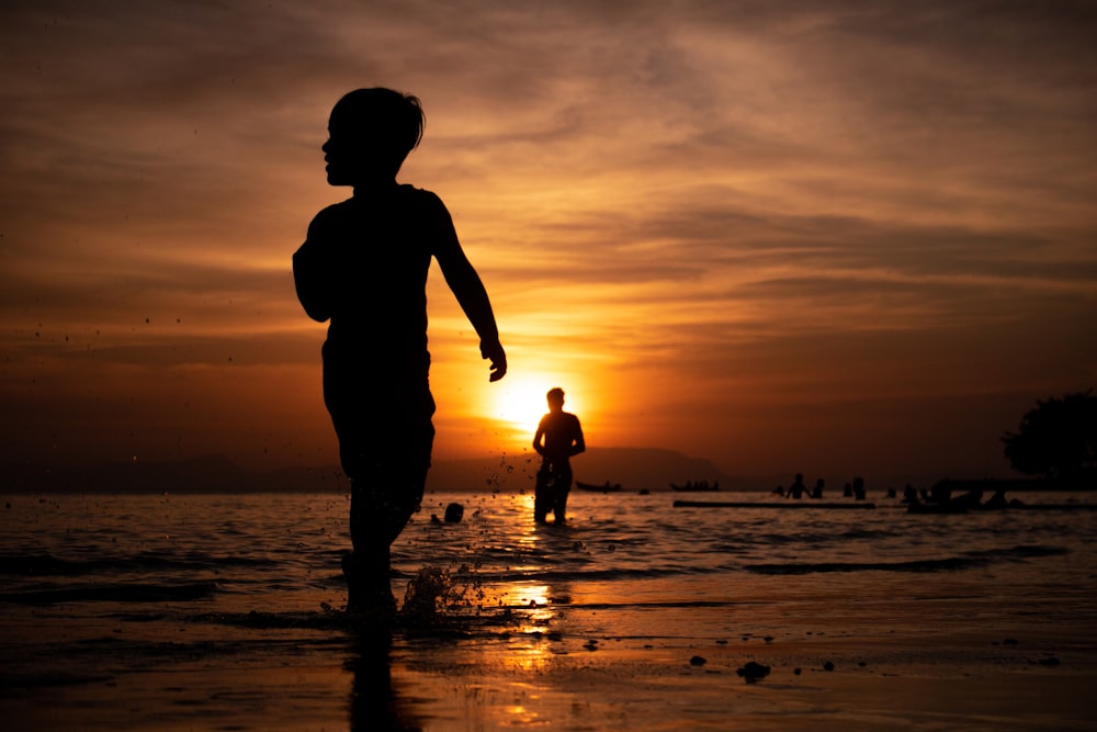 a person is walking on the beach at sunset