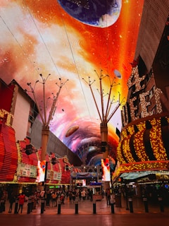 a brightly lit shopping mall with a colorful sky painted on the ceiling