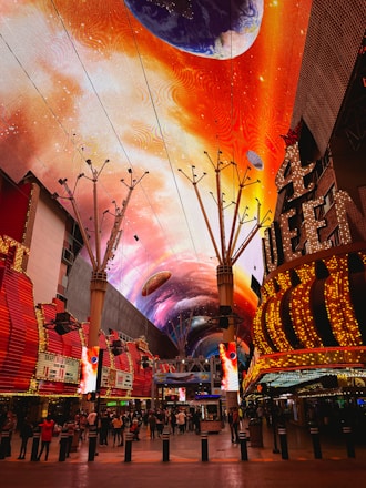 a brightly lit shopping mall with a colorful sky painted on the ceiling