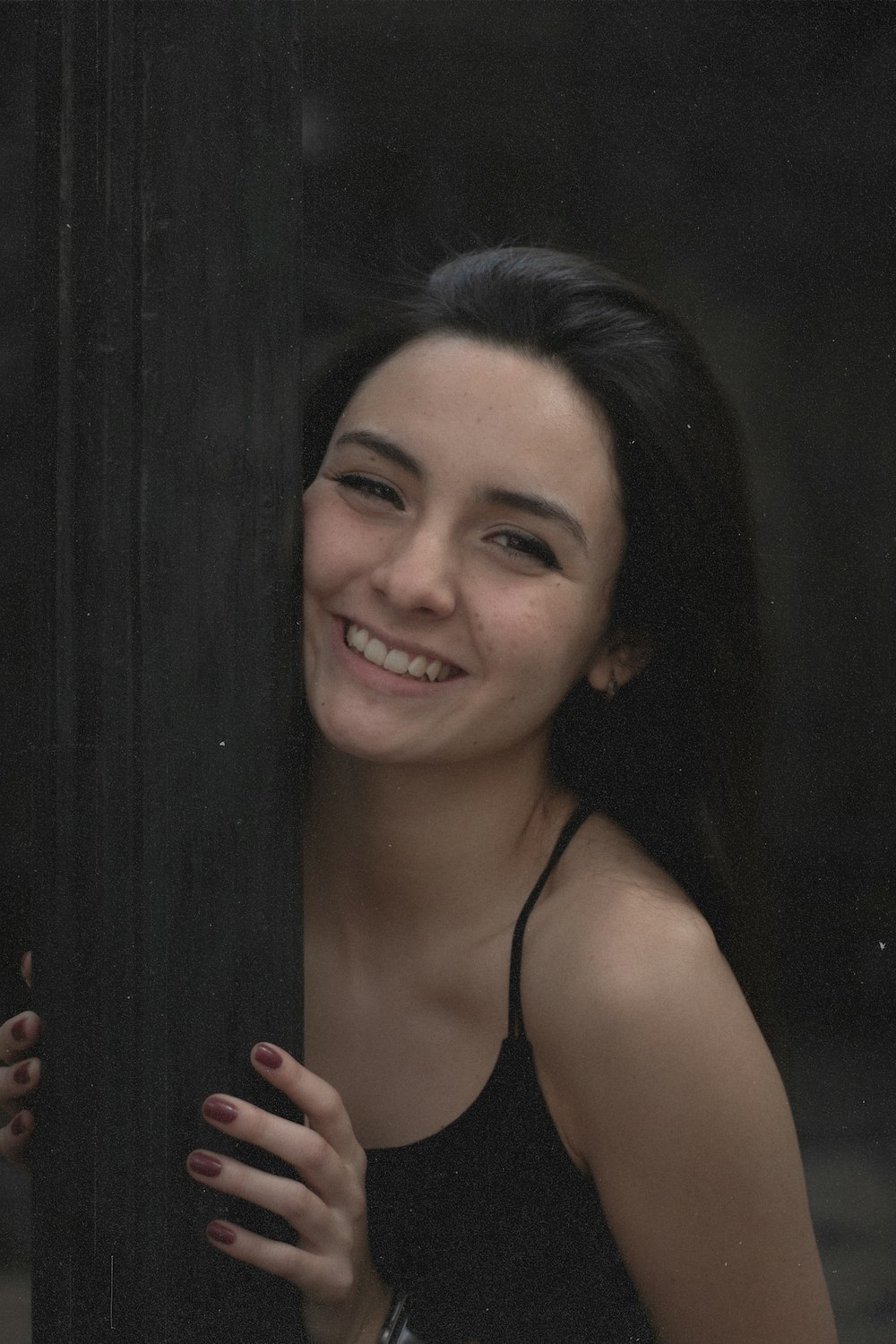 a woman is smiling while leaning against a pole