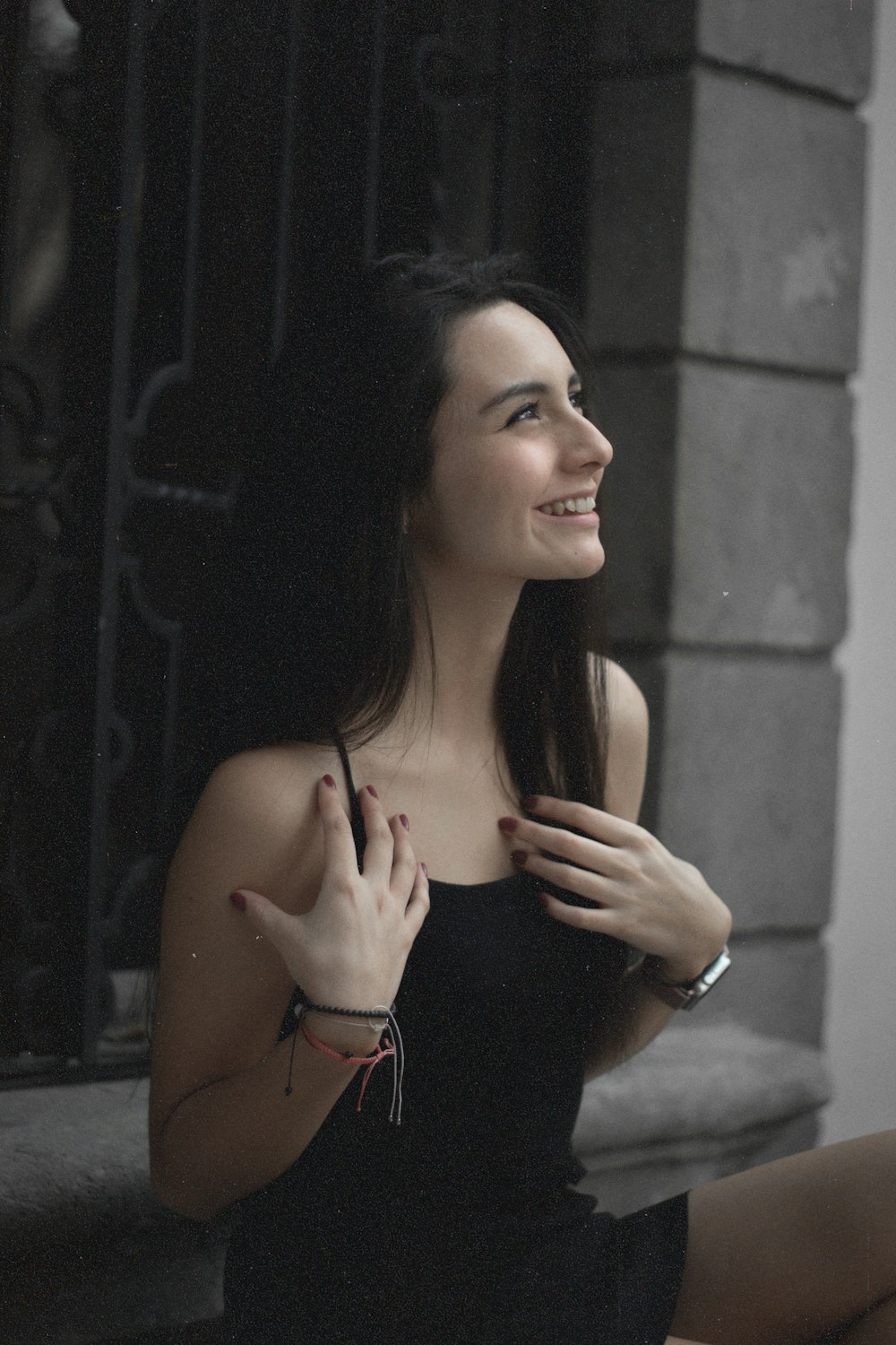 a woman in a black dress sitting on a window sill