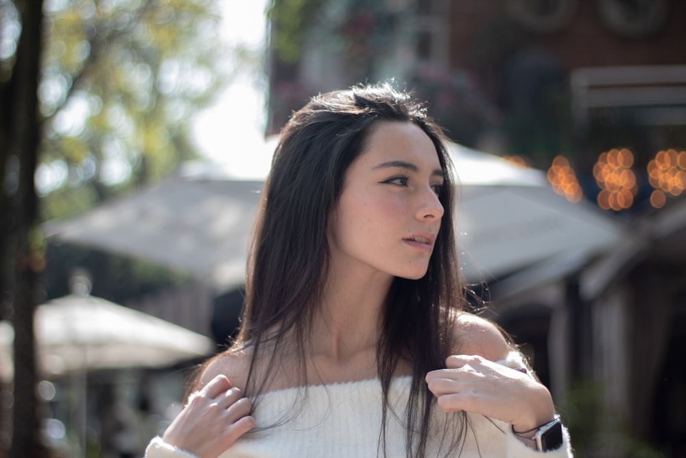 a woman in a white sweater looking off into the distance