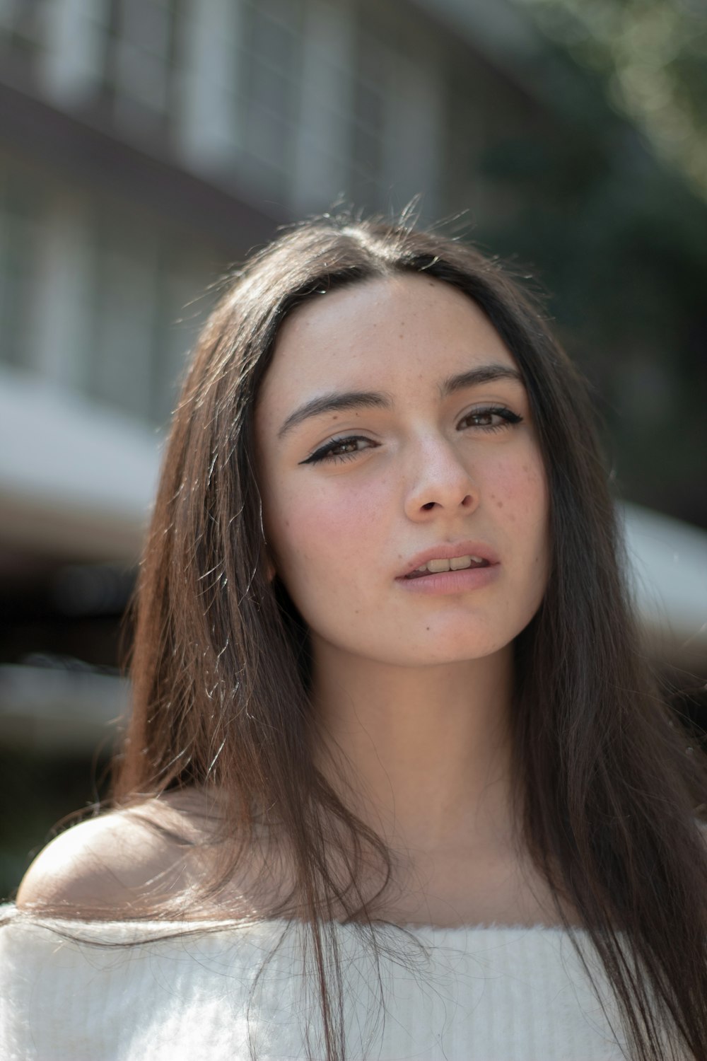 a woman with long brown hair and a white sweater