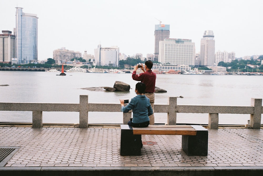 a couple of people sitting on top of a wooden bench