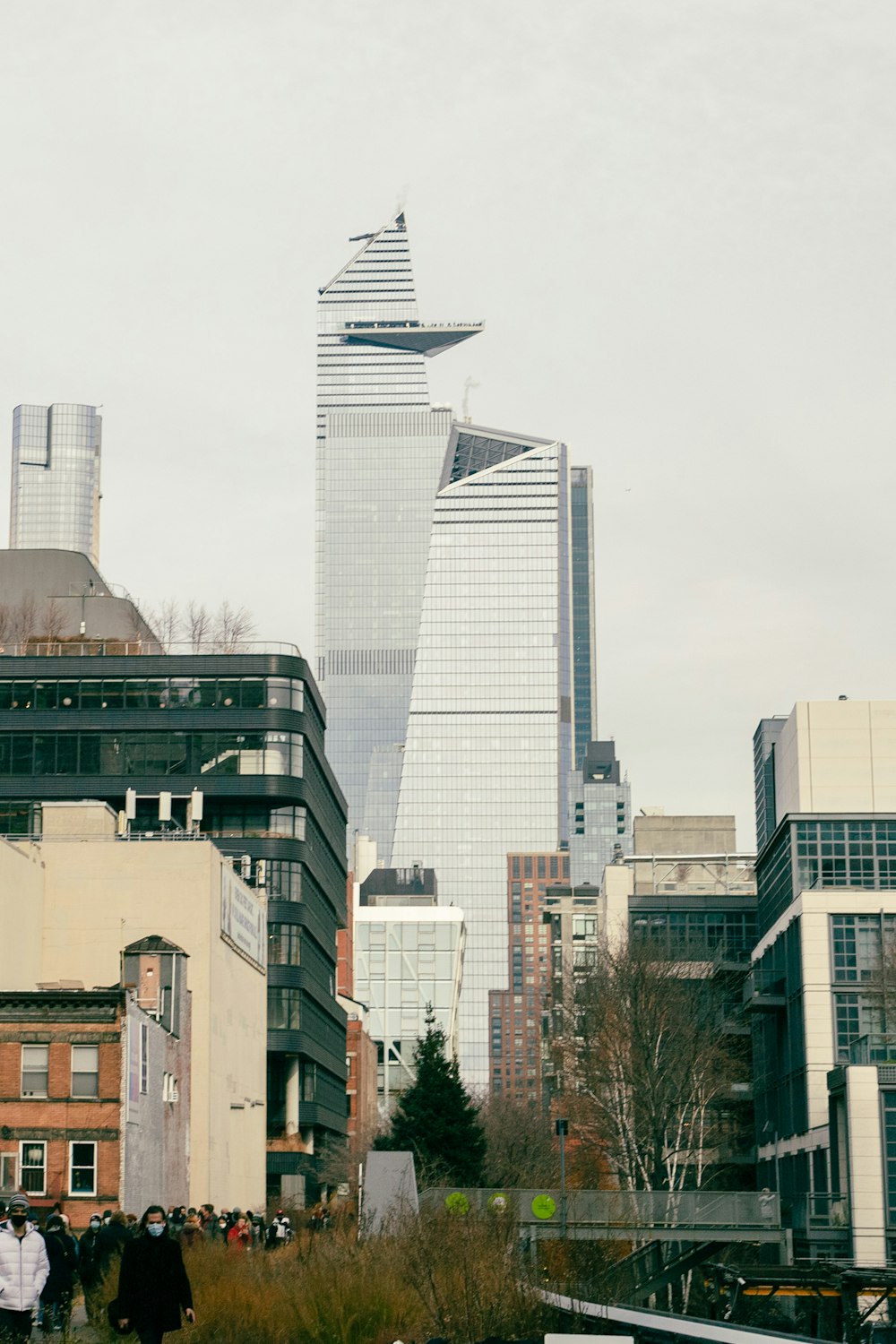 a group of people walking down a street next to tall buildings