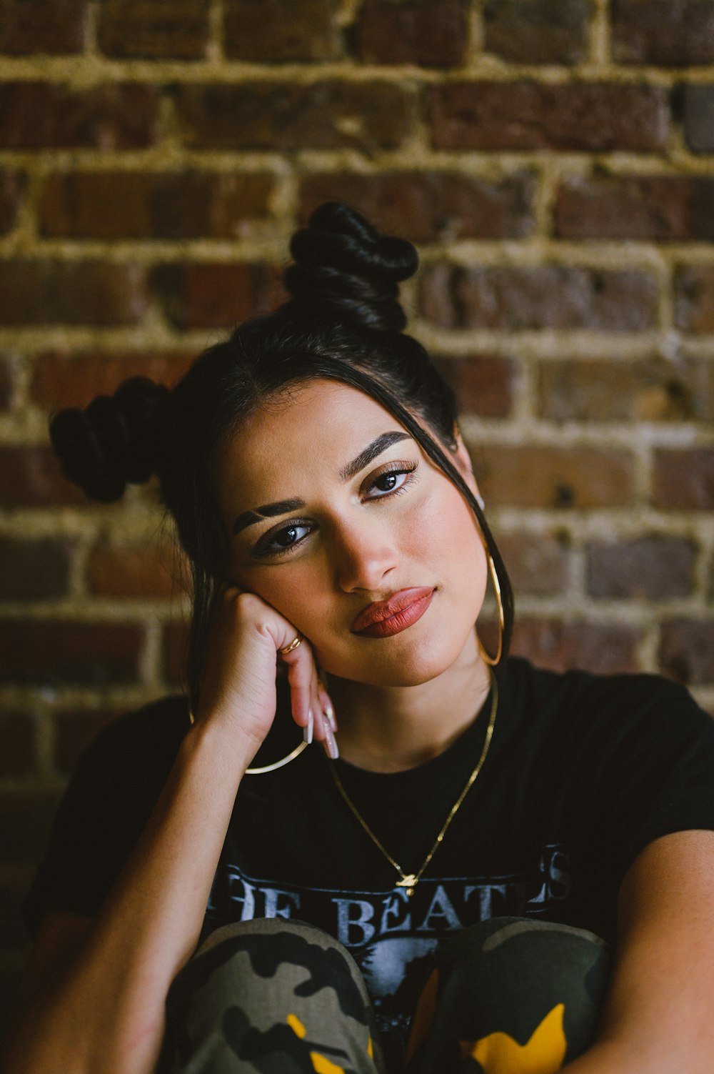 a woman sitting in front of a brick wall