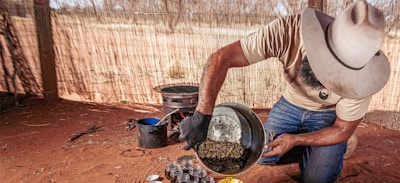 Traditional Himalayan collector carefully harvesting Salajit resin at high altitude.