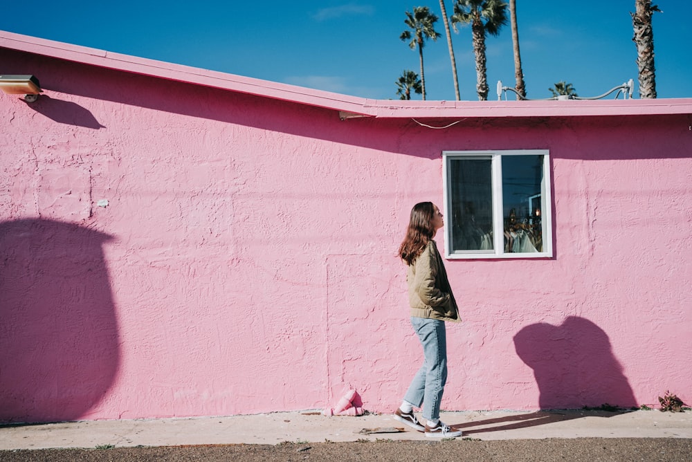 a woman standing in front of a pink building