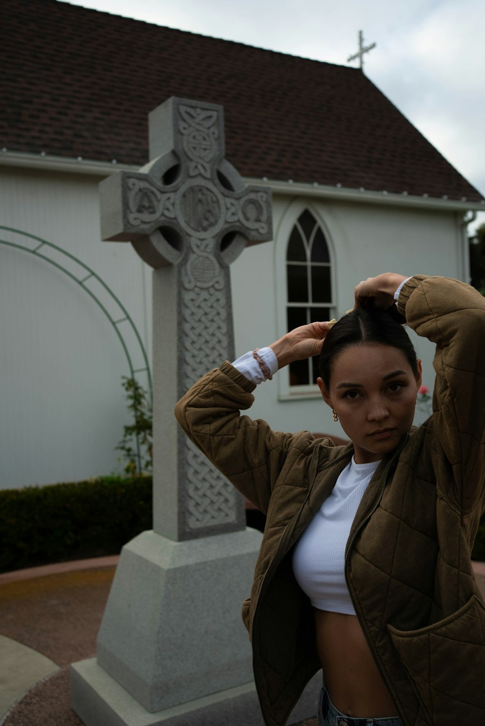 a woman is standing in front of a cross