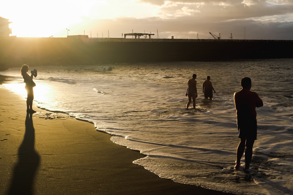 a group of people standing on top of a beach next to the ocean