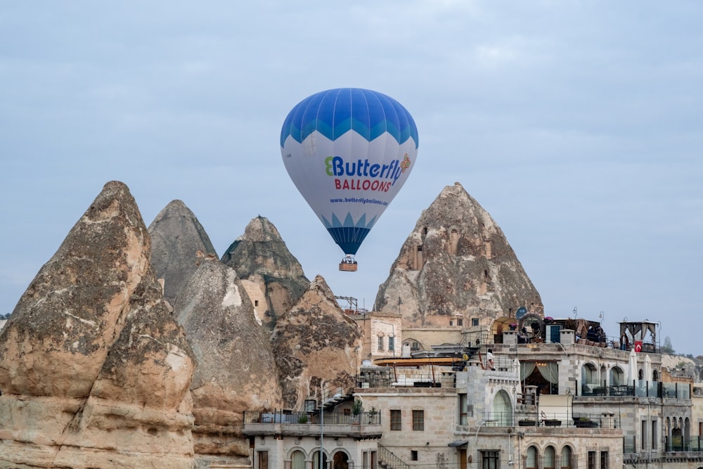 a blue and white hot air balloon flying over a city