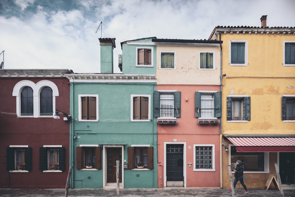 uma pessoa passando por uma fileira de edifícios coloridos