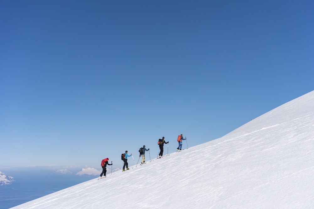 Un grupo de personas montando esquís en la cima de una pista cubierta de nieve