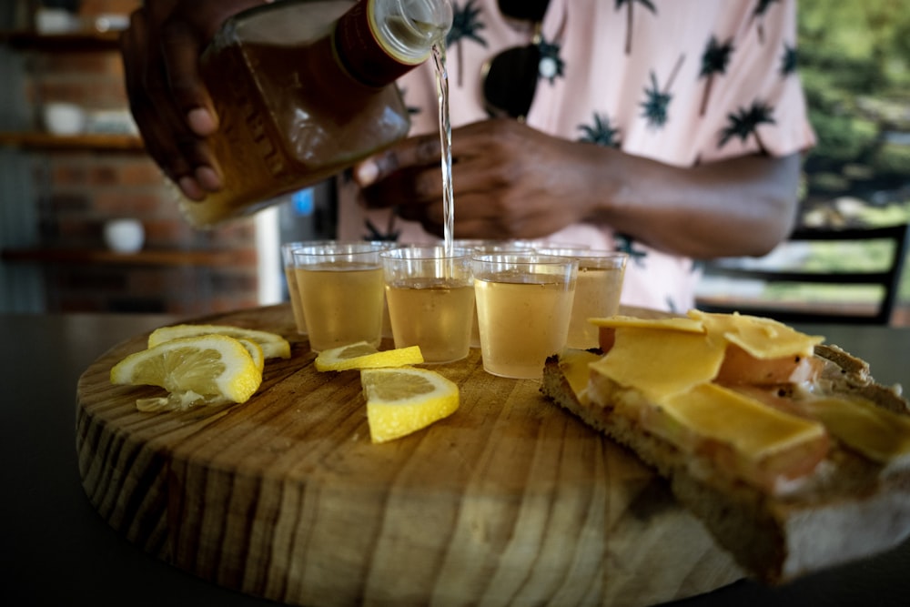 a person pours a pitcher of beer over a tray of cheese and lemon slices