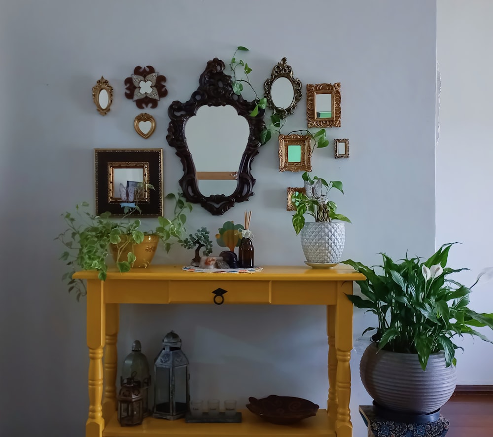 a yellow table with a mirror and potted plants