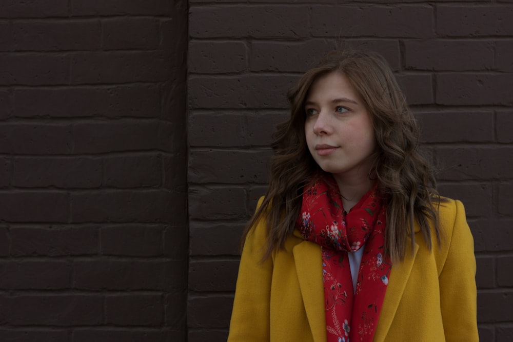 a young girl wearing a yellow coat and a red scarf