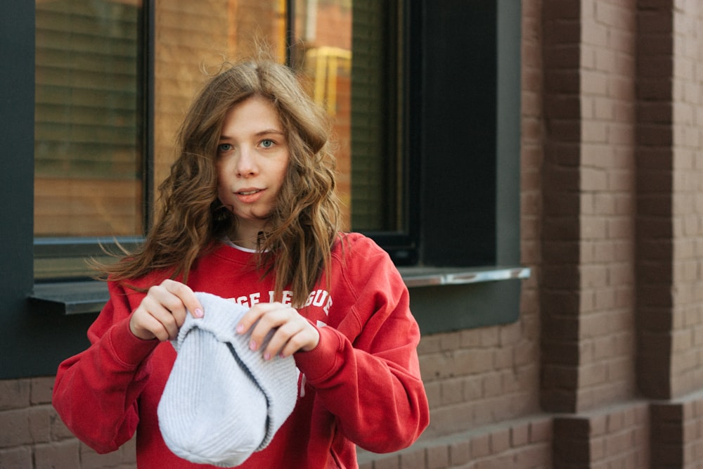 a girl in a red sweatshirt is holding a white bag