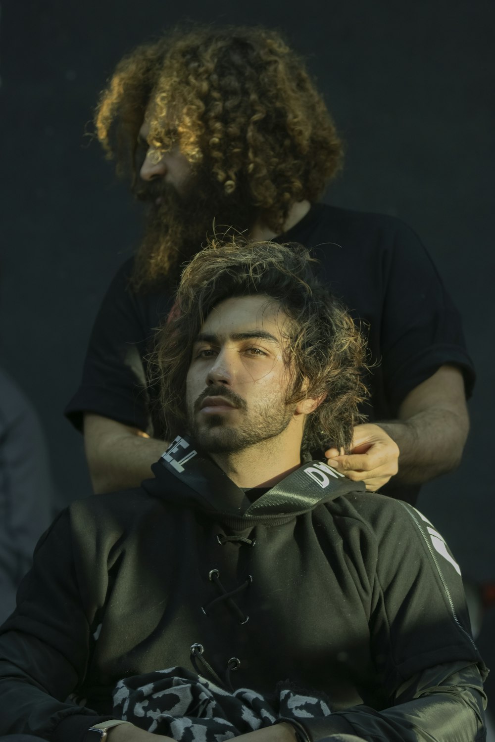 a man with long hair sitting in a chair