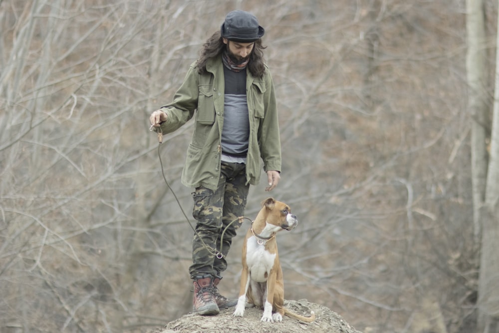 a man standing on top of a rock next to a brown and white dog