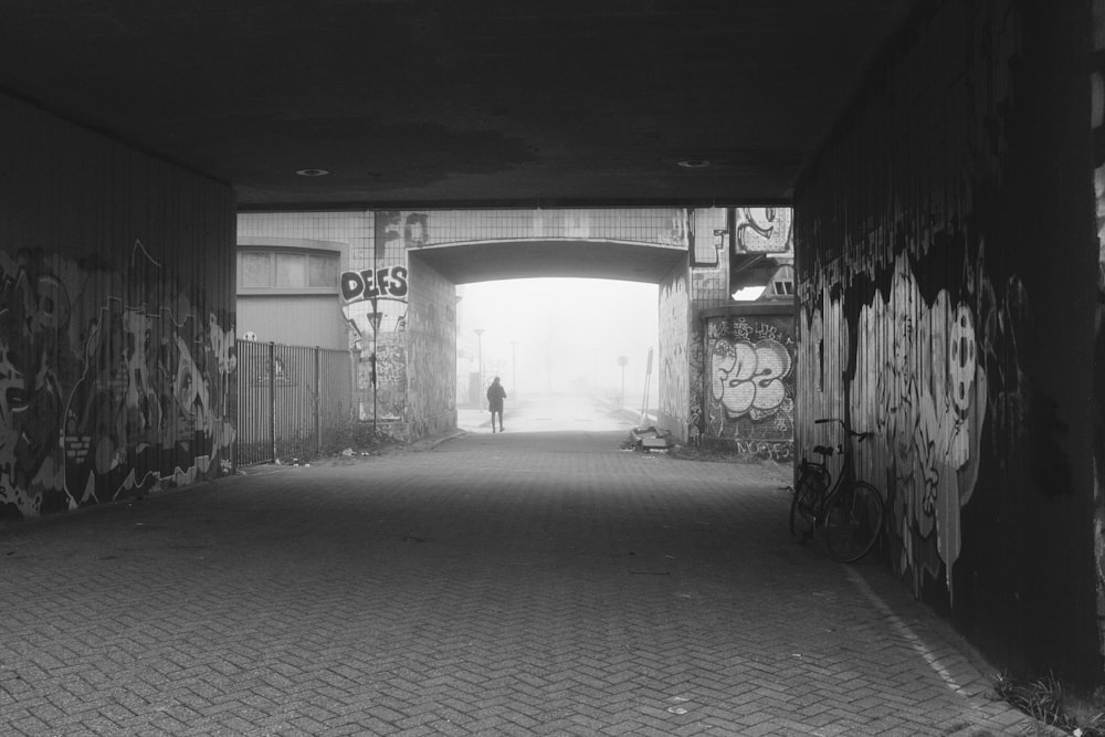 a black and white photo of a person standing in a tunnel