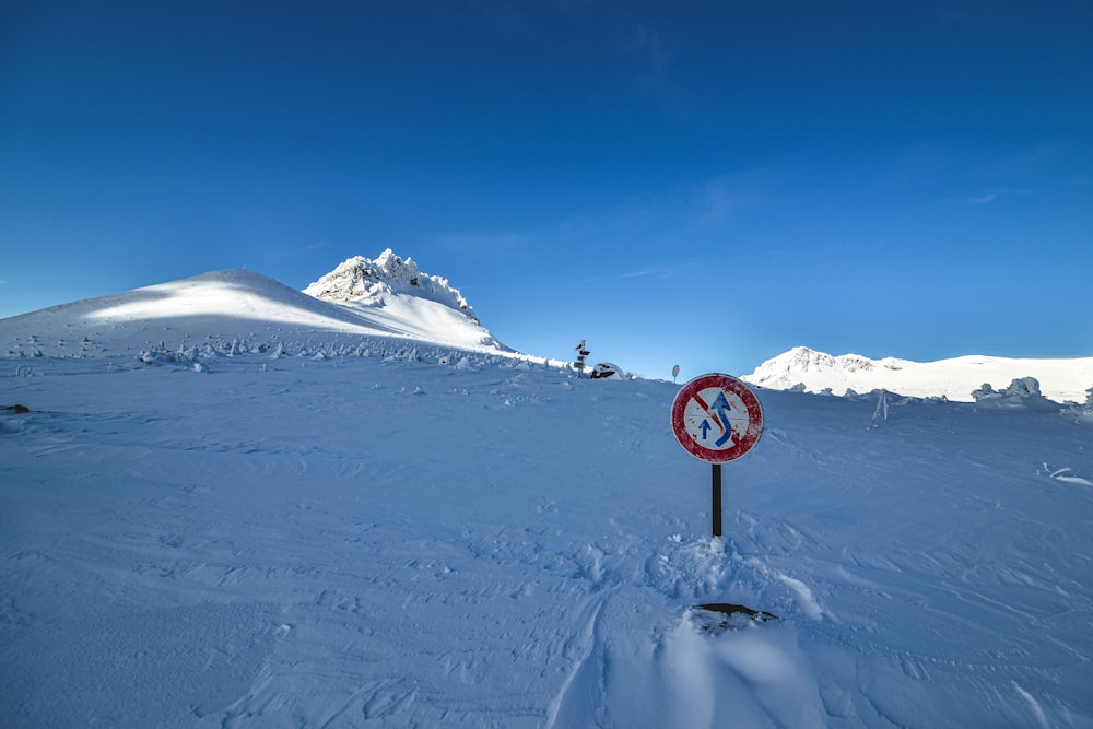 a red and white sign sitting on the side of a snow covered slope