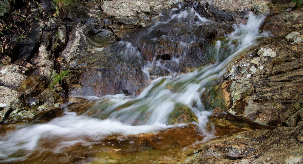 a stream of water running down a rocky hillside