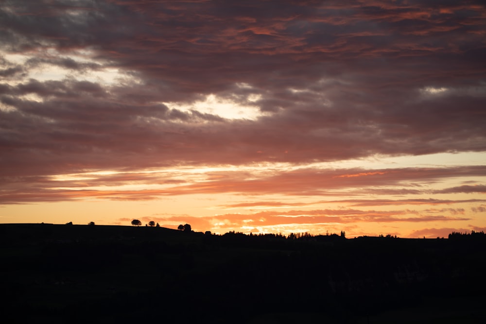 the sun is setting over the horizon of a field