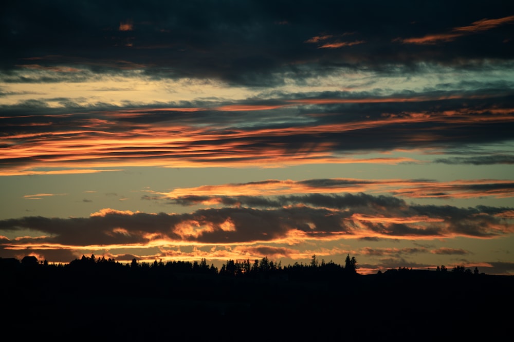 a sunset with clouds and trees in the background