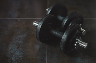 Close-up of neon green-accented dumbbells on a sleek black gym floor.
