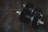 Close-up shot of a sleek pair of black dumbbells resting on a wooden floor.