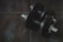Close-up shot of a sleek pair of black dumbbells resting on a wooden floor.