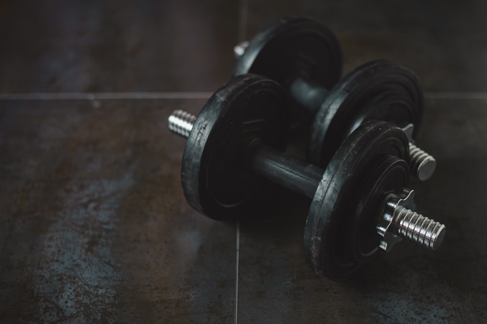 a pair of dumbbells sitting on a tiled floor