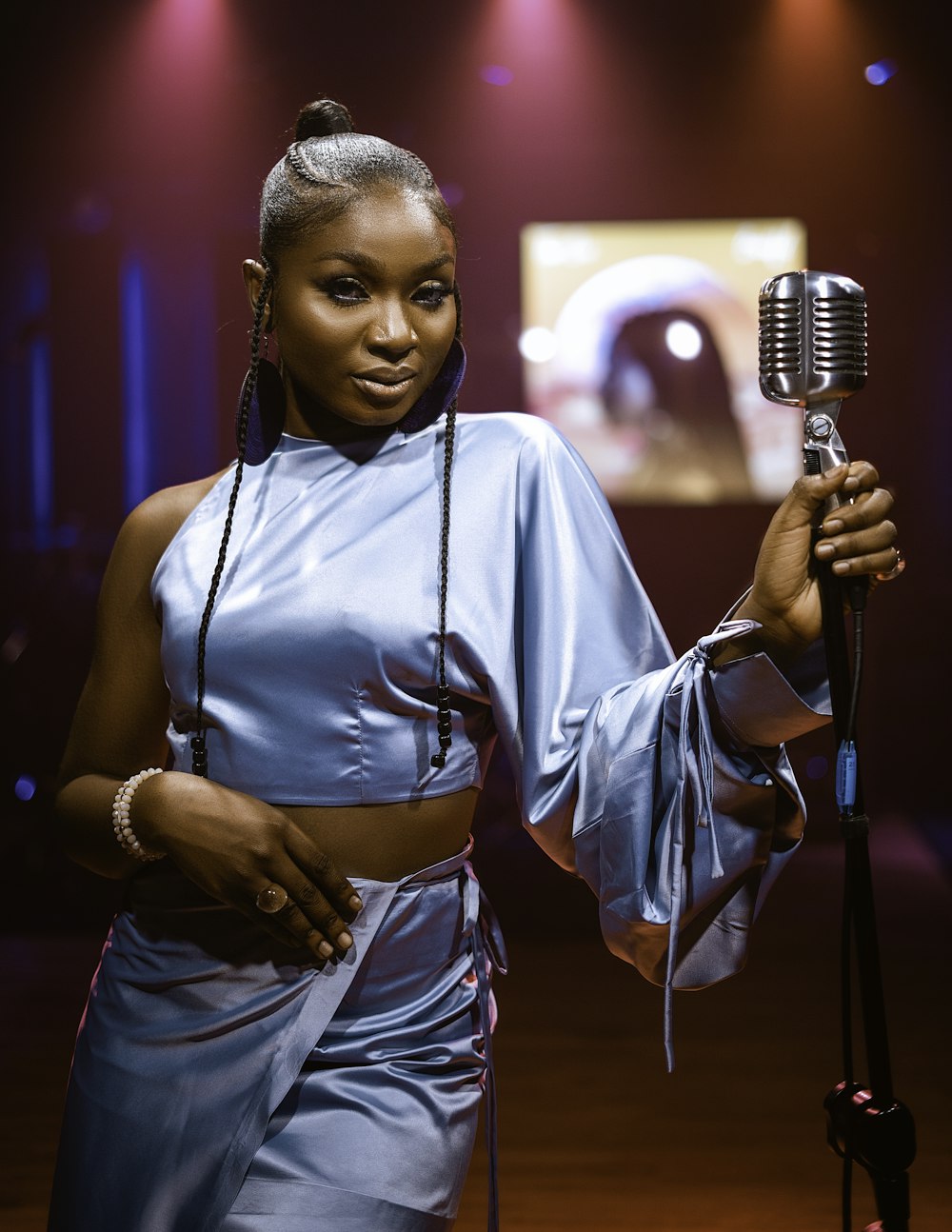 a woman holding a microphone in front of a stage