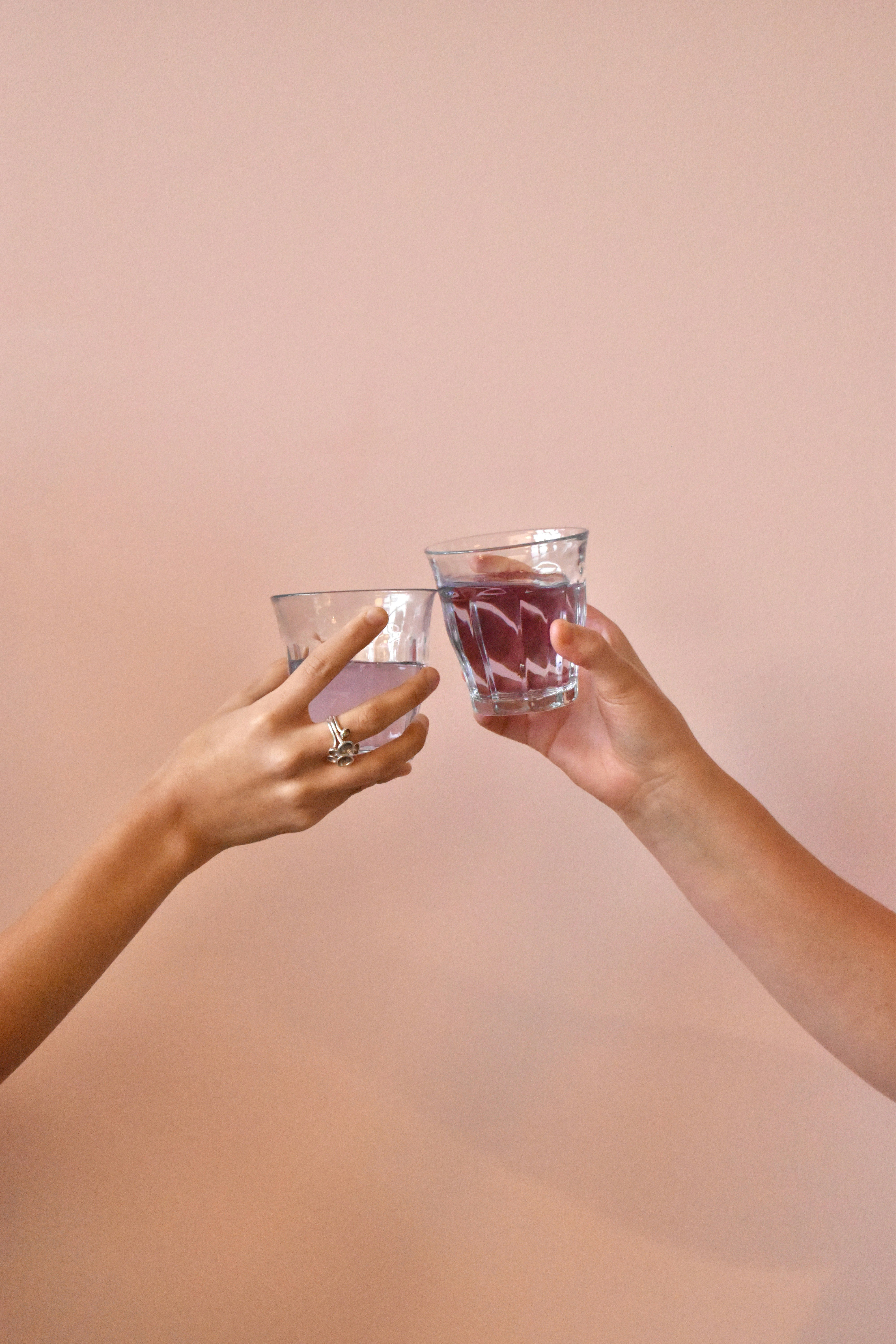 deux mains tenant un verre de liquide rouge