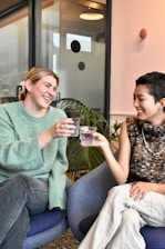 a couple of women sitting on top of a blue chair