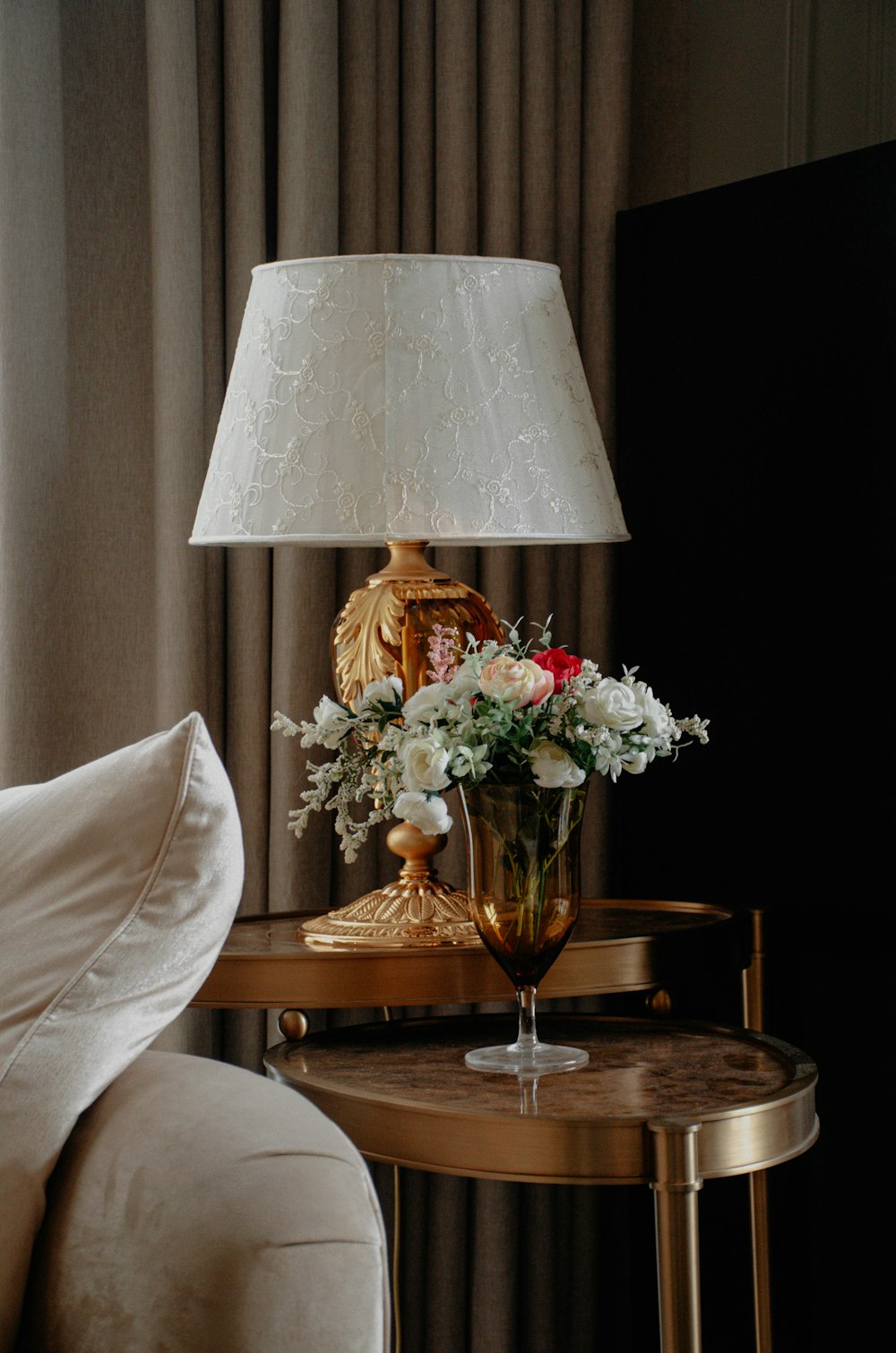 a table with a vase of flowers and a lamp on it