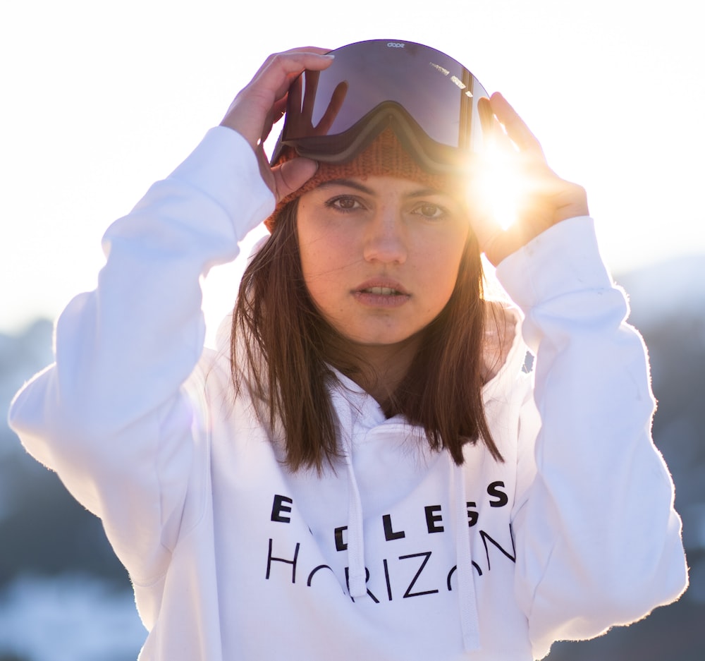 a woman wearing ski goggles and a white hoodie