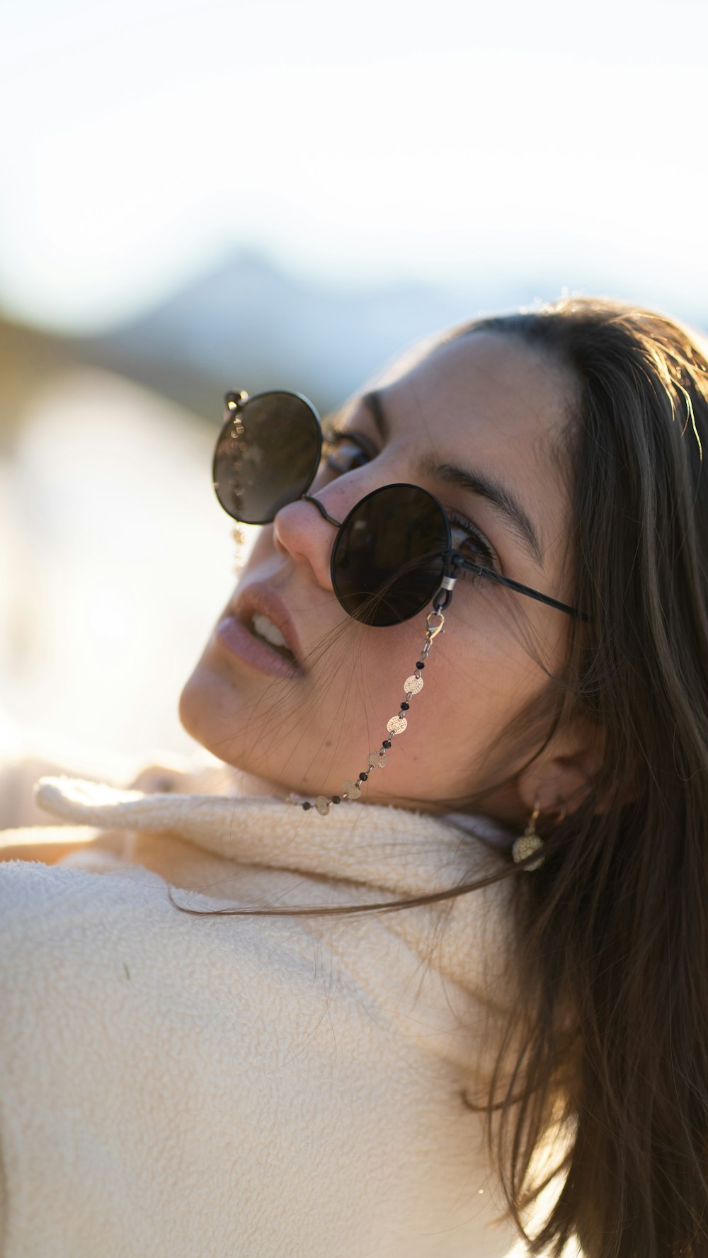 a woman wearing sunglasses and a white sweater