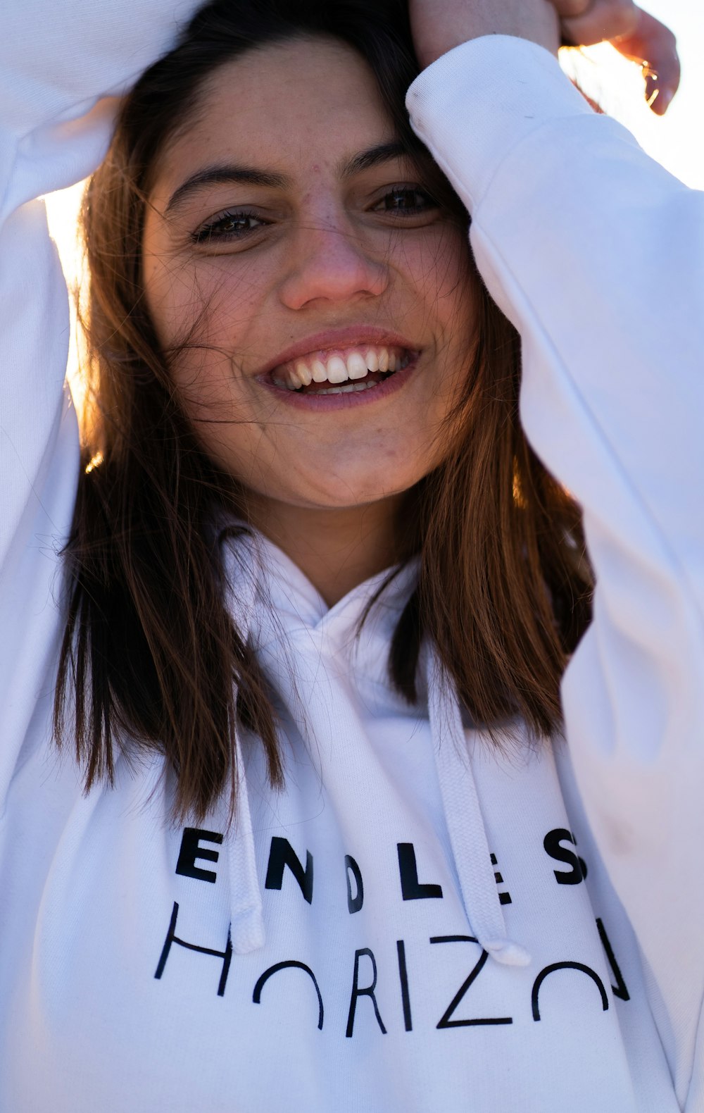 a woman with long hair wearing a white hoodie