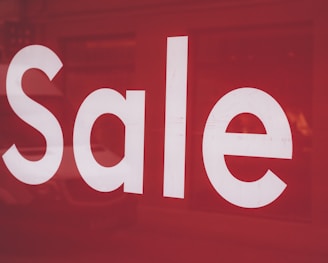 a close up of a red sale sign with a van in the background