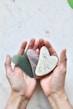 two hands holding two heart shaped pieces of soap