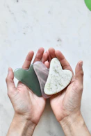 A close-up of hands holding a heart-shaped stone.