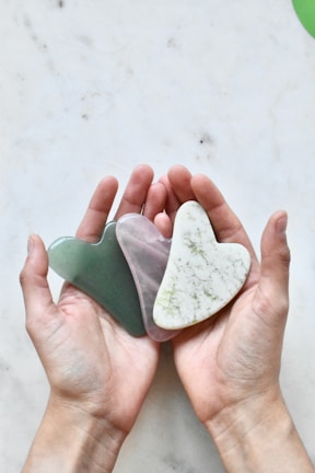 Close-up of hands holding a heart-shaped stone, representing care and emotional support.